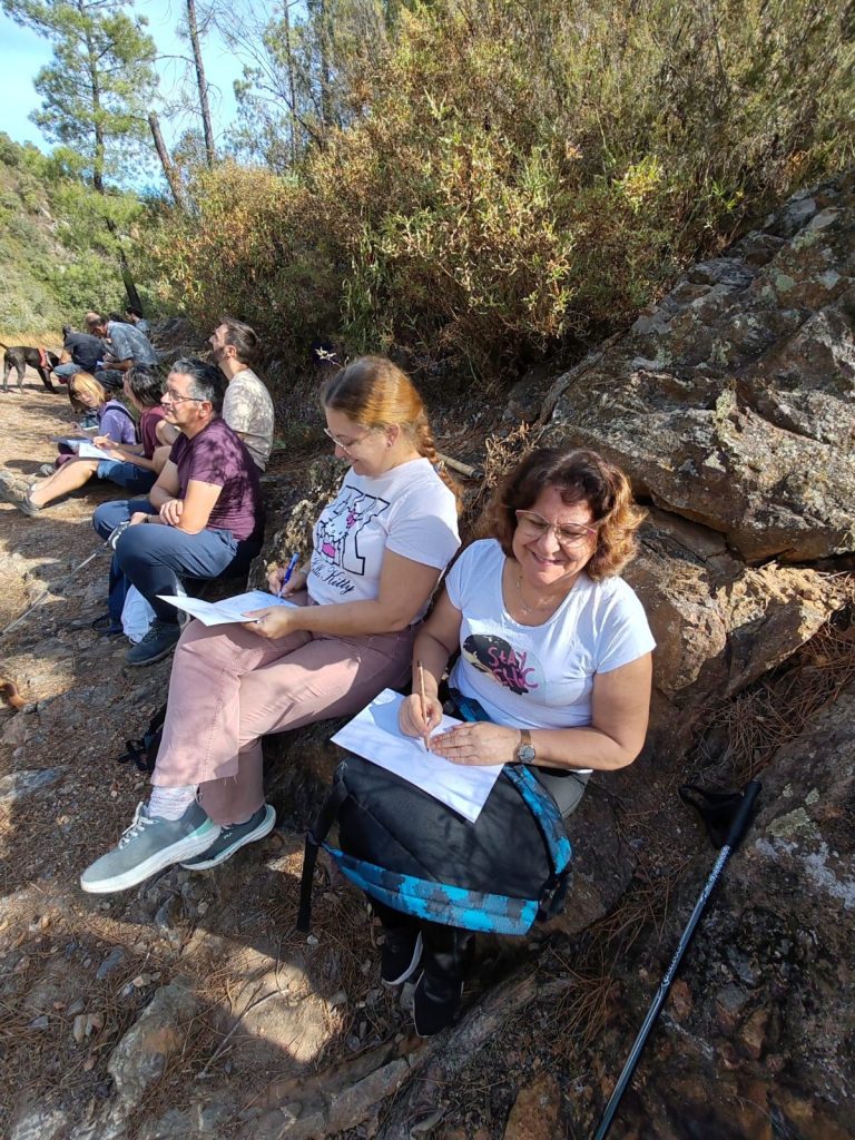 Dos participantes dibujando junto a una roca en la Georruta de Los Molinos